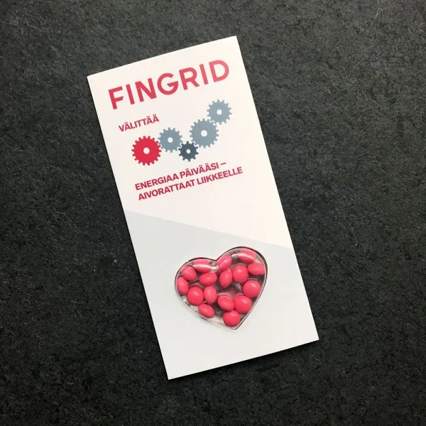 Produktbild von Bister mit Herzform-Bonbon-Dragees in Geschmacksrichtungen: Apfel (grüne Dragees), Erdbeere (dunkles Pink), Minze (weiß), Orange (orange Dragees), Zitrone (gelbe Dragees), Waldfrucht (blaue Dragees).