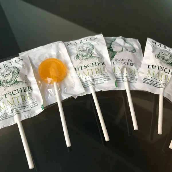 Produktbild von Kleiner Lutscher mit individuellem Druck auf der weißen Seite, flach mit transparenter Folie und verfügbar in mehreren Farben (ø 30 x 95 mm), Mindestmenge: 5.000 Stück.